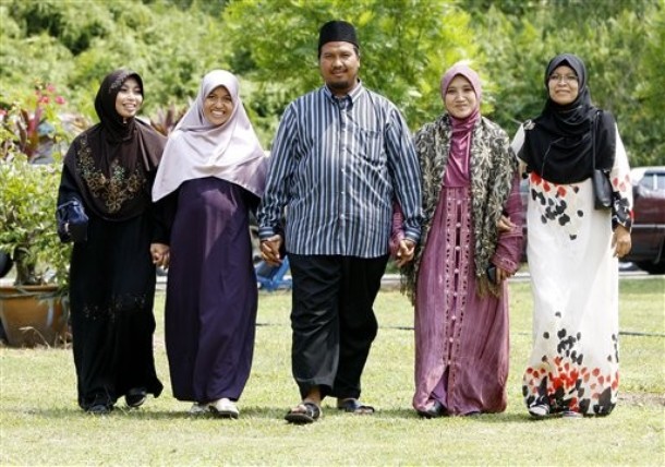 In this  Aug. 15, 2009 photo, polygamist Mohammad Inaamulillah Bin Ashaari, center, is shown with his four wives, from left, Rohaiza Esa, Ummu Habibah Raihaw , Nurul Azwa Mohd Ani,and Ummu Ammarah Asmis at the "Ikhwan Polygamy Club Family Day" in Rawang, north of Kuala Lumpur, Malaysia. Polygamy is legal for Muslims in Malaysia, though not widespread. The Ashaari clan believes it should be. Last month, the sprawling family launched a Polygamy Club that seeks to promote plural marriages for what it says are noble aims, such as helping single mothers, prostitutes and older women find husbands. (AP Photo/Mark Baker)